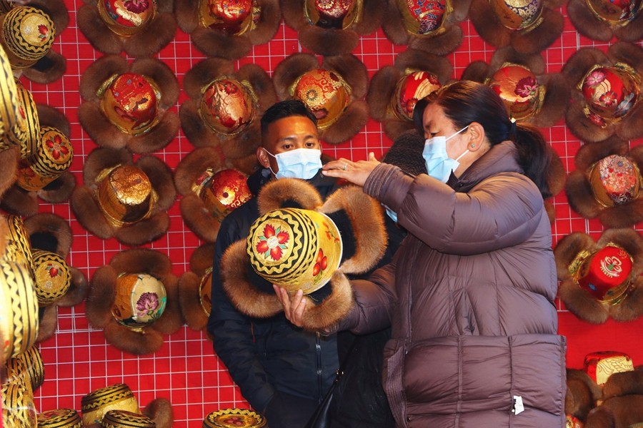 图为第45届物交会现场,顾客在挑选金丝缎帽。.jpg